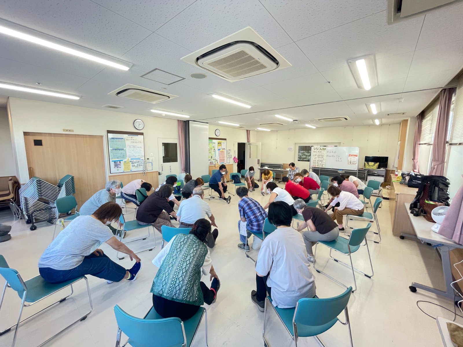 参加者の足元と手のクローズアップ。専門職が伴走しながら体を動かす場面